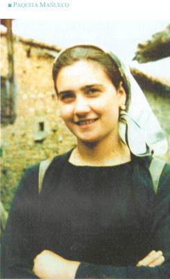 Smiling woman with headscarf in rural setting.