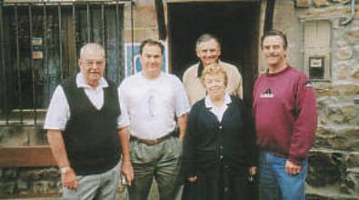 Five people standing outside a stone building.