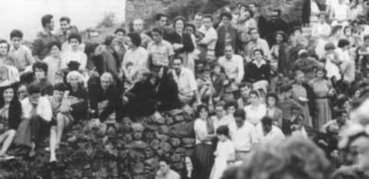 Group of people sitting on stone wall.