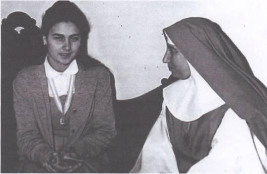 Young woman and nun sitting together, talking.