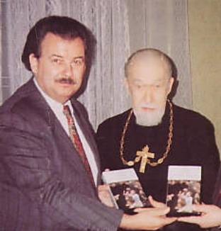 Two men holding books, one wearing cross.