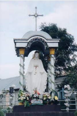 Religious statue under arch with flowers.