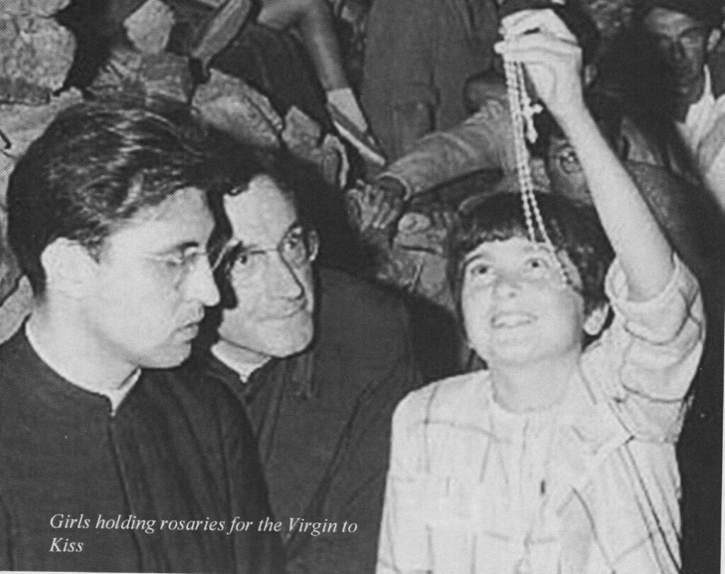 Girl holding rosary with two men watching.