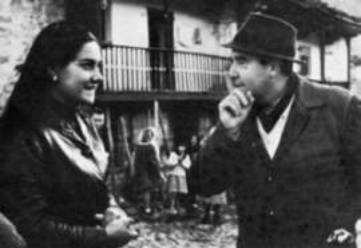 Man and woman talking in village setting.