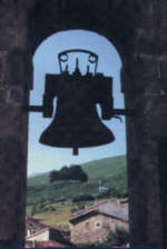 Silhouette of bell against rural landscape.