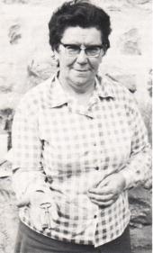 Woman holding keys, wearing checkered shirt.