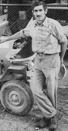 Man standing beside a vintage tractor.