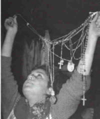 Person holding rosaries and religious necklaces overhead.