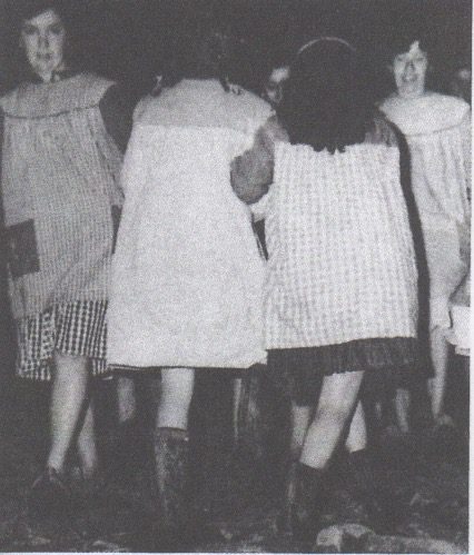 Women in vintage dresses, standing together outdoors.